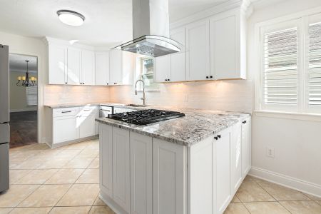 Custom kitchen remodel in Kenner featuring white shaker cabinetry and peninsula bar top